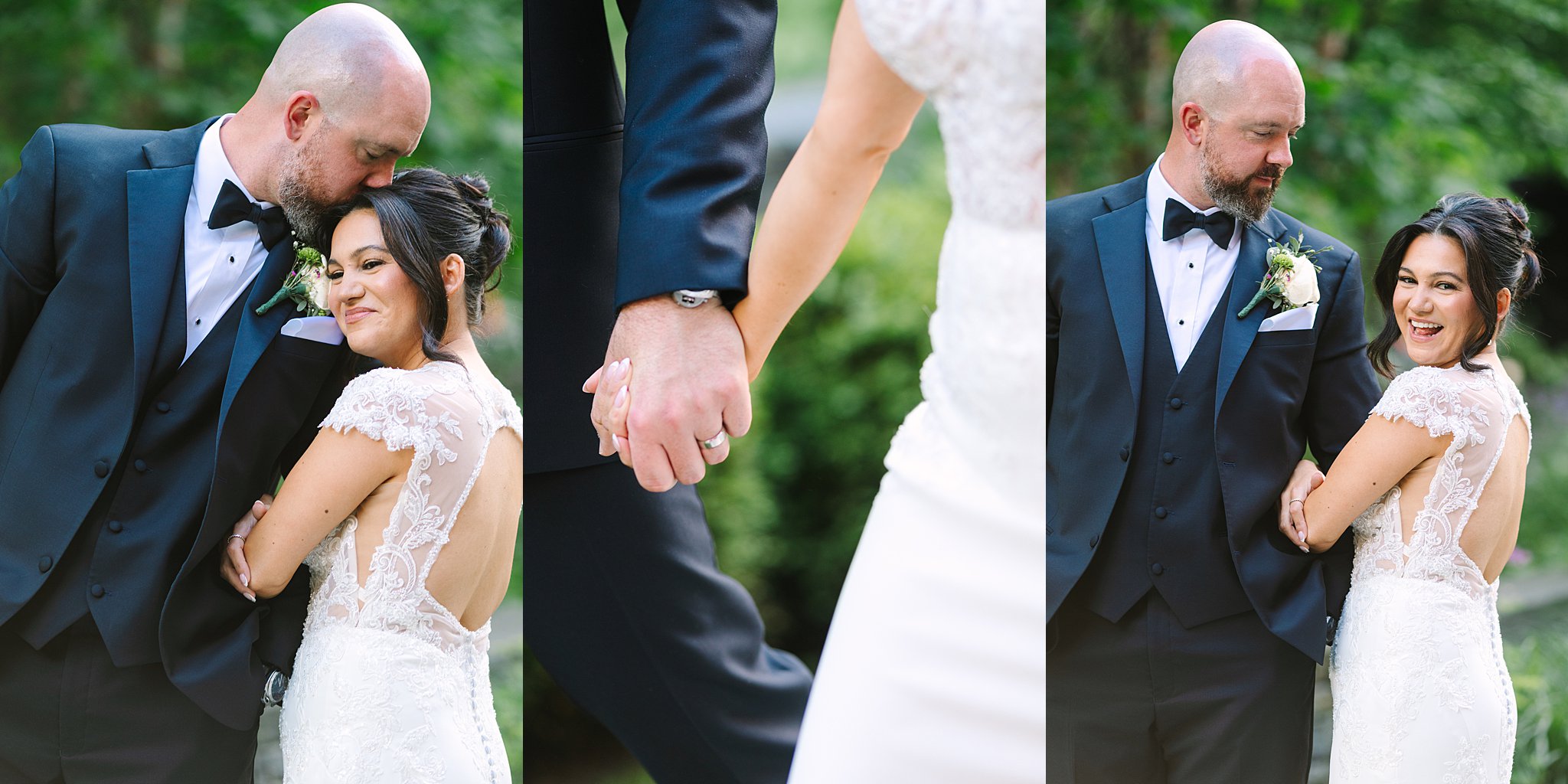 A bride in a lace wedding dress and a groom in a black tuxedo embrace, hold hands, and smile at each other outdoors, surrounded by greenery.