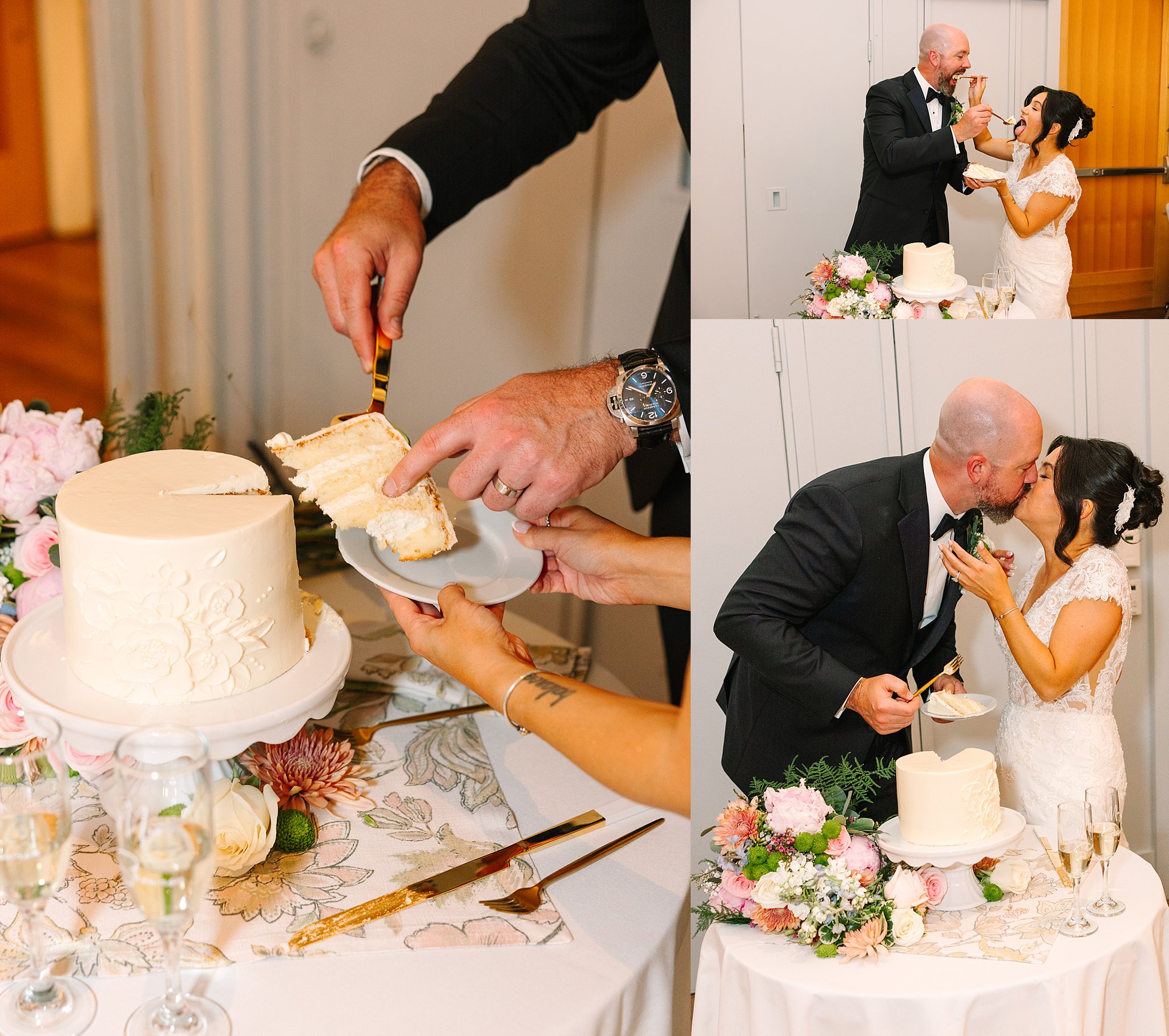A bride and groom cut and share a slice of their wedding cake, feeding each other and sharing a kiss beside a decorated cake table with flowers and champagne.