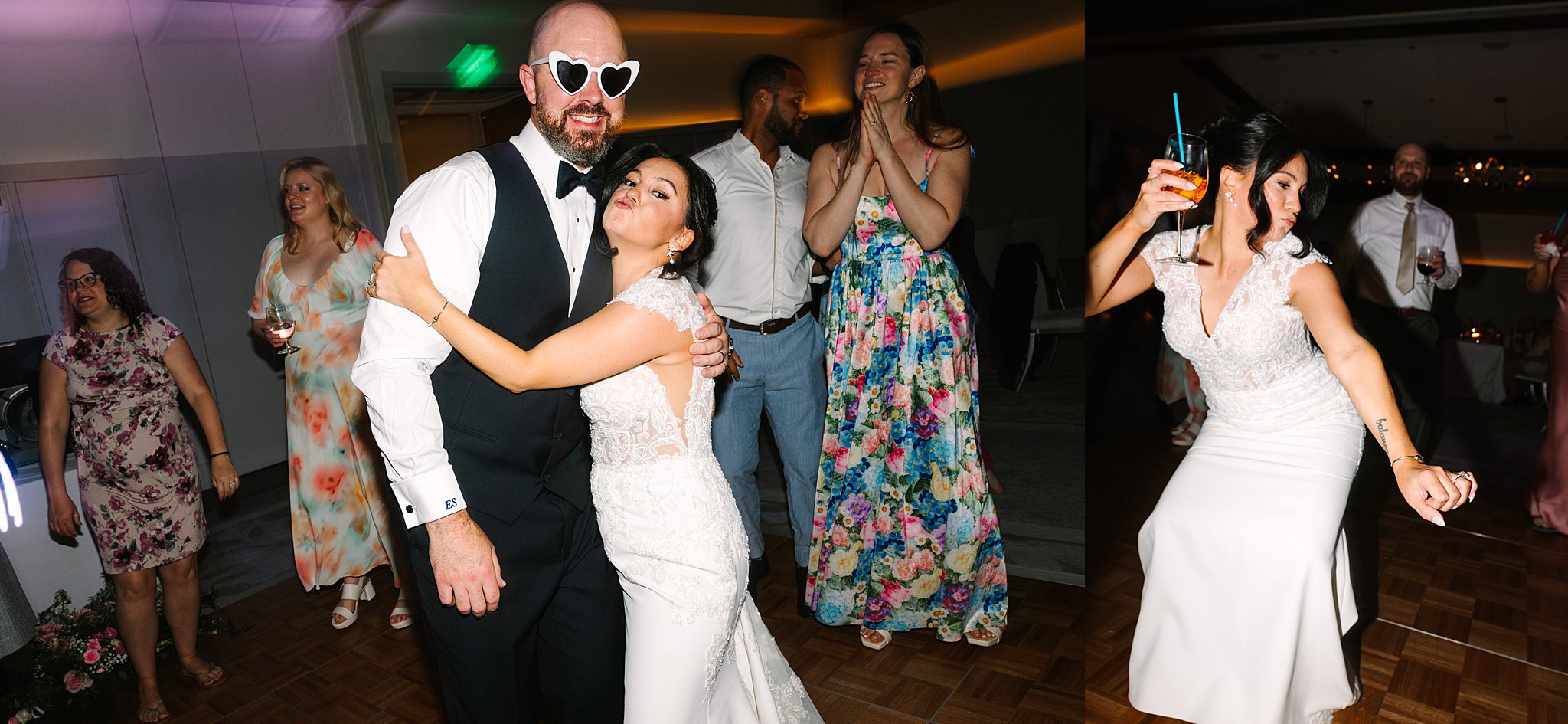 A bride in a white dress hugs a man in a tuxedo wearing heart-shaped sunglasses while guests in colorful outfits smile and dance at a lively wedding reception.