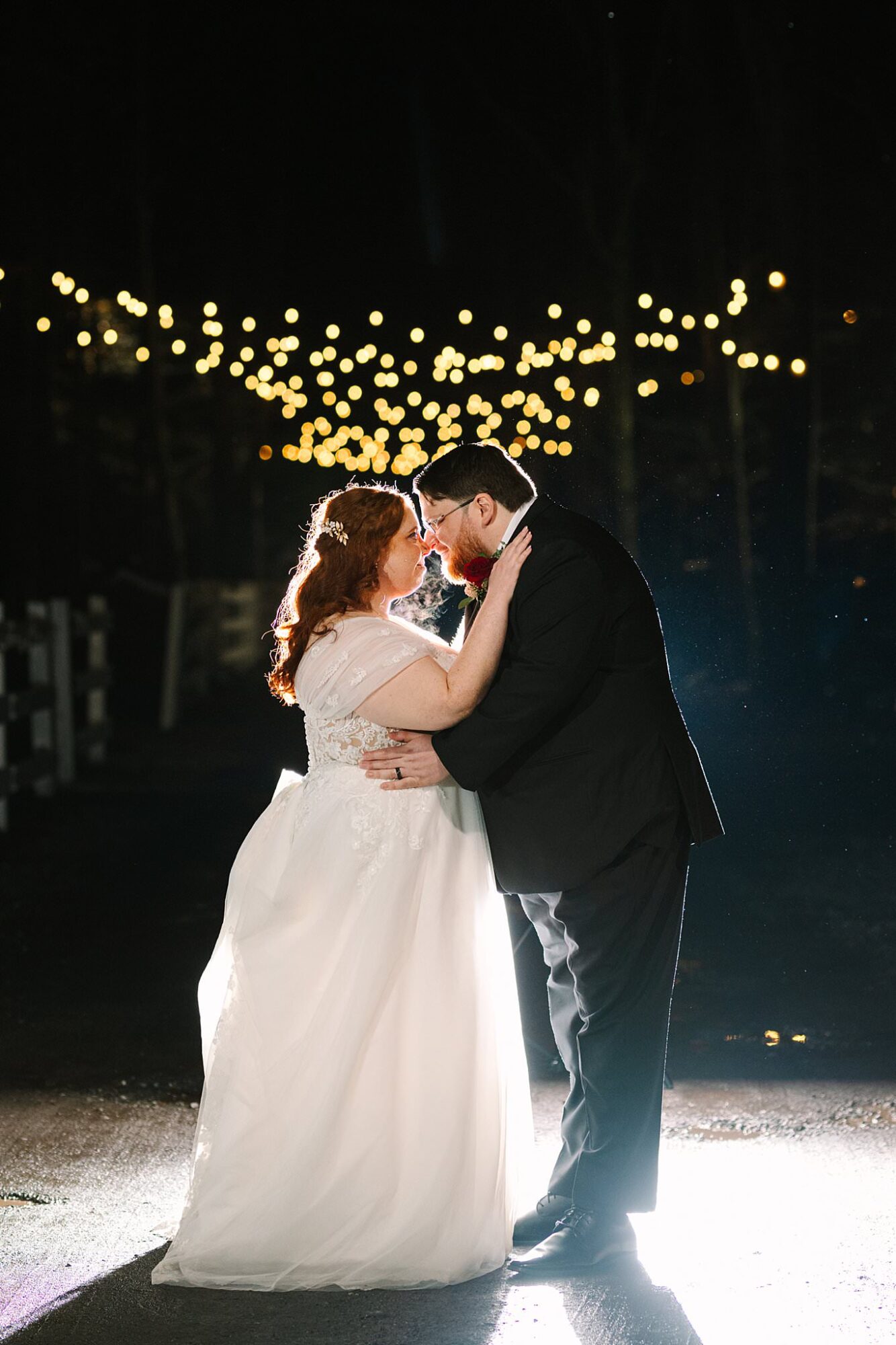 Couple dancing under twink;e lights outside at night at Five Bridge Inn barn wedding