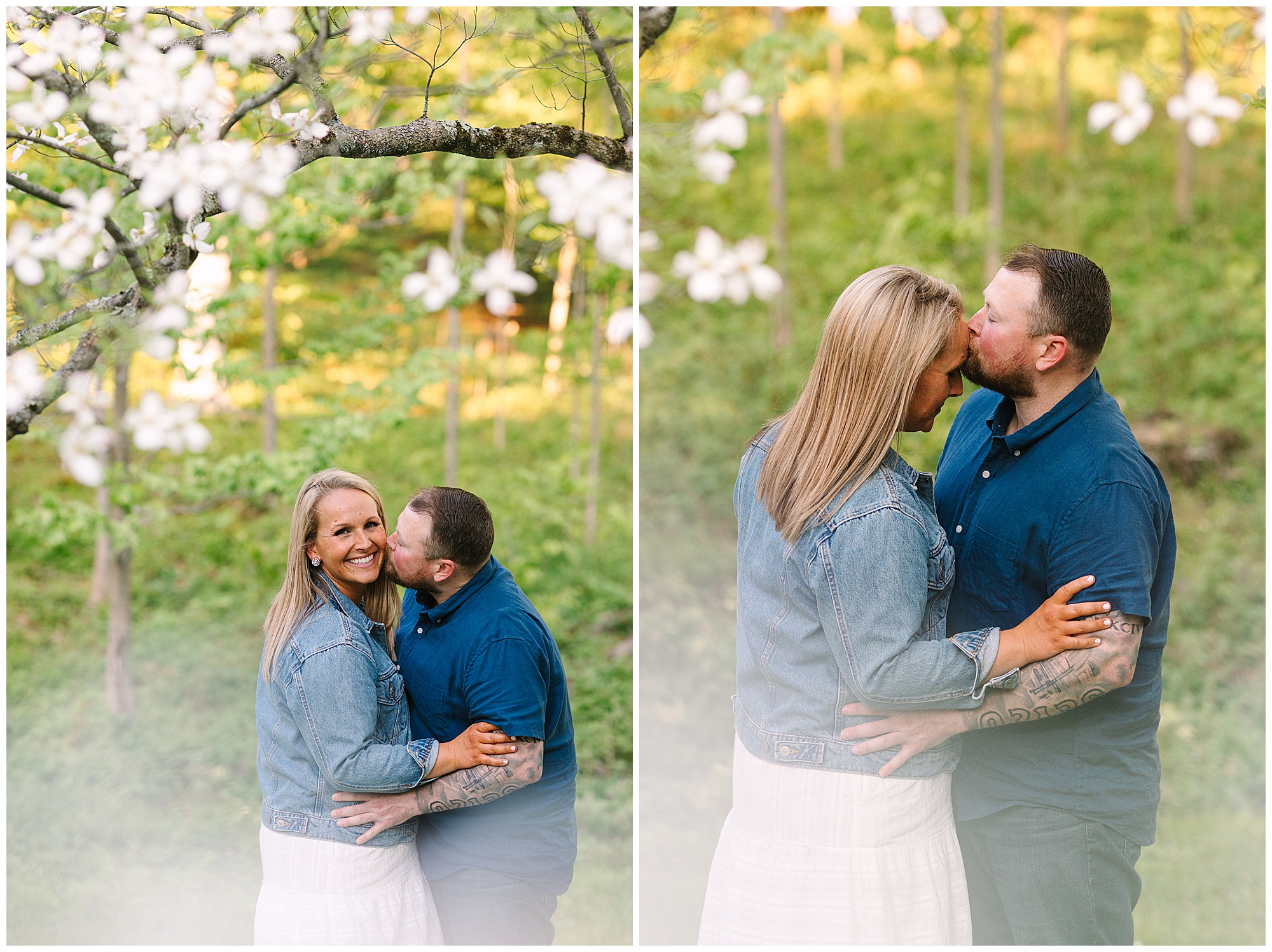 A couple stands outdoors among blooming trees. The man, in a blue shirt, embraces and kisses the smiling woman, who wears a denim jacket and white skirt. They look happy and affectionate, surrounded by greenery and flowers.