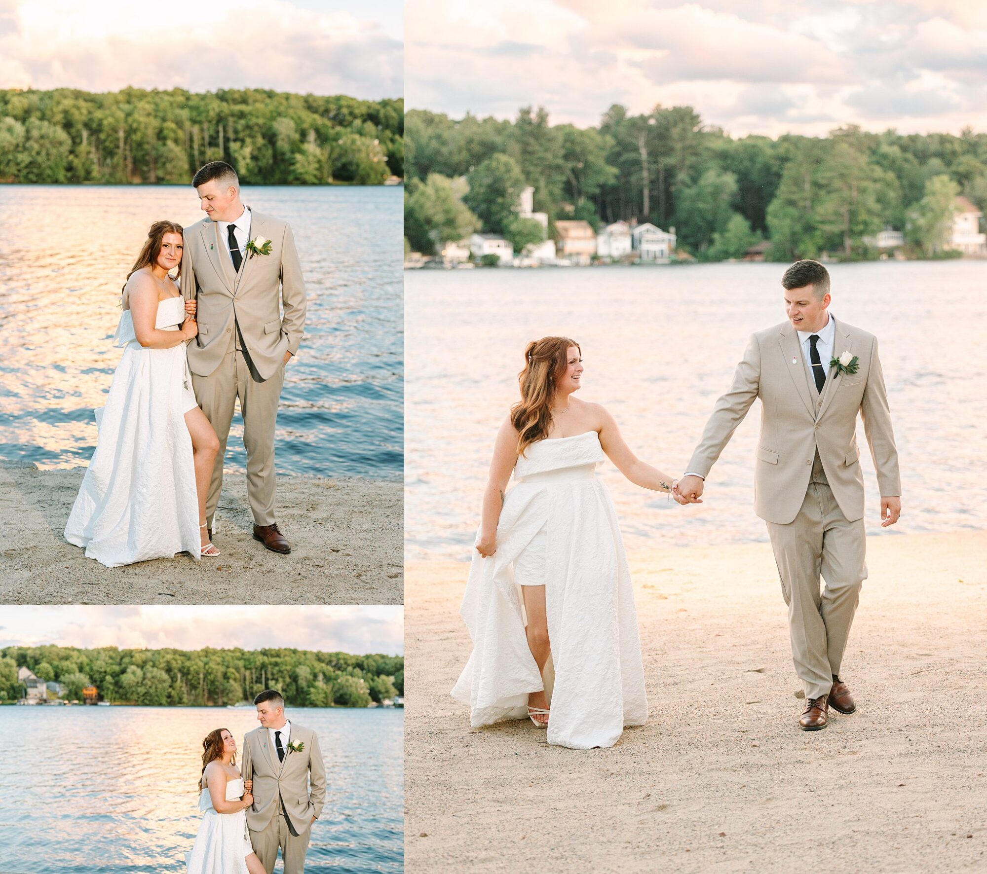 A bride in a strapless white dress and a groom in a beige suit pose and walk together on a sandy lakeshore, with trees and water in the background under a partly cloudy sky.