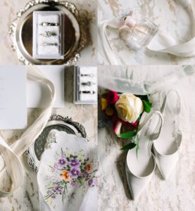 A collage of wedding items: rings in boxes, a perfume bottle with a ribbon, a floral handkerchief, a bouquet with white shoes, and a wedding invitation on a textured surface.