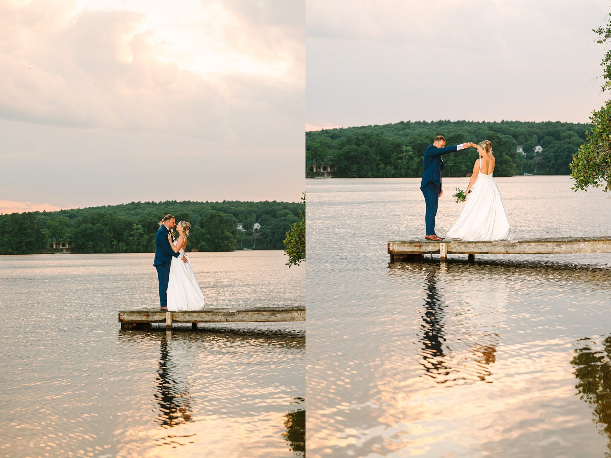 A bride and groom stand on a wooden dock by a lake, surrounded by trees. The groom holds the brides hand, and they gaze at each other affectionately under a cloudy sky.