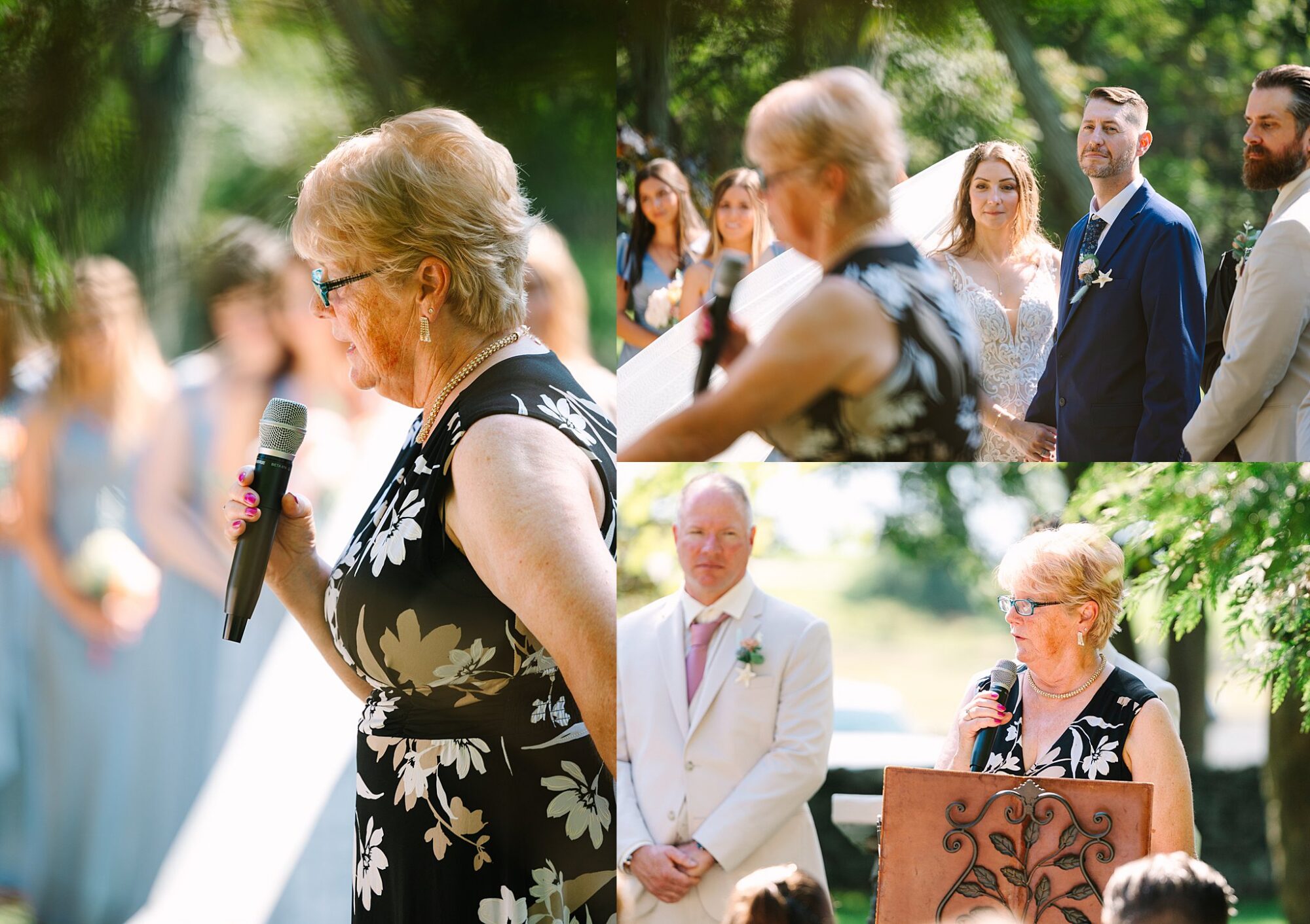 A woman in a black floral dress speaks into a microphone at an outdoor wedding ceremony. The bride, groom, guests, and officiant listen attentively in a sunny, green setting.