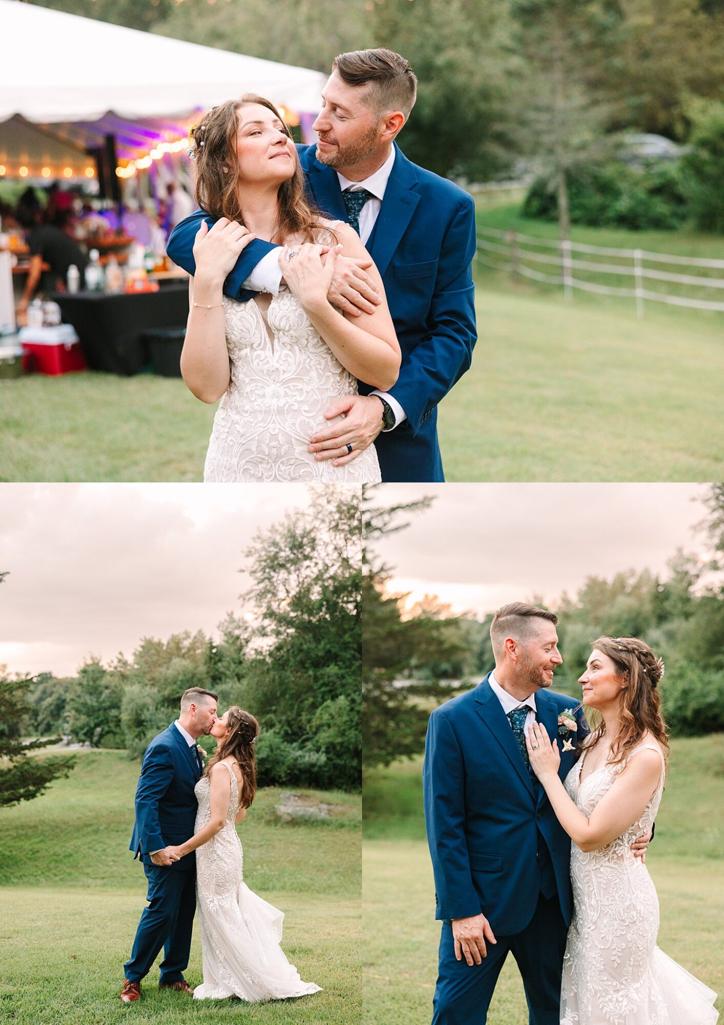 A bride in a lace dress and a groom in a blue suit embrace and dance outdoors on a grassy lawn, with trees and a decorated tent in the background.