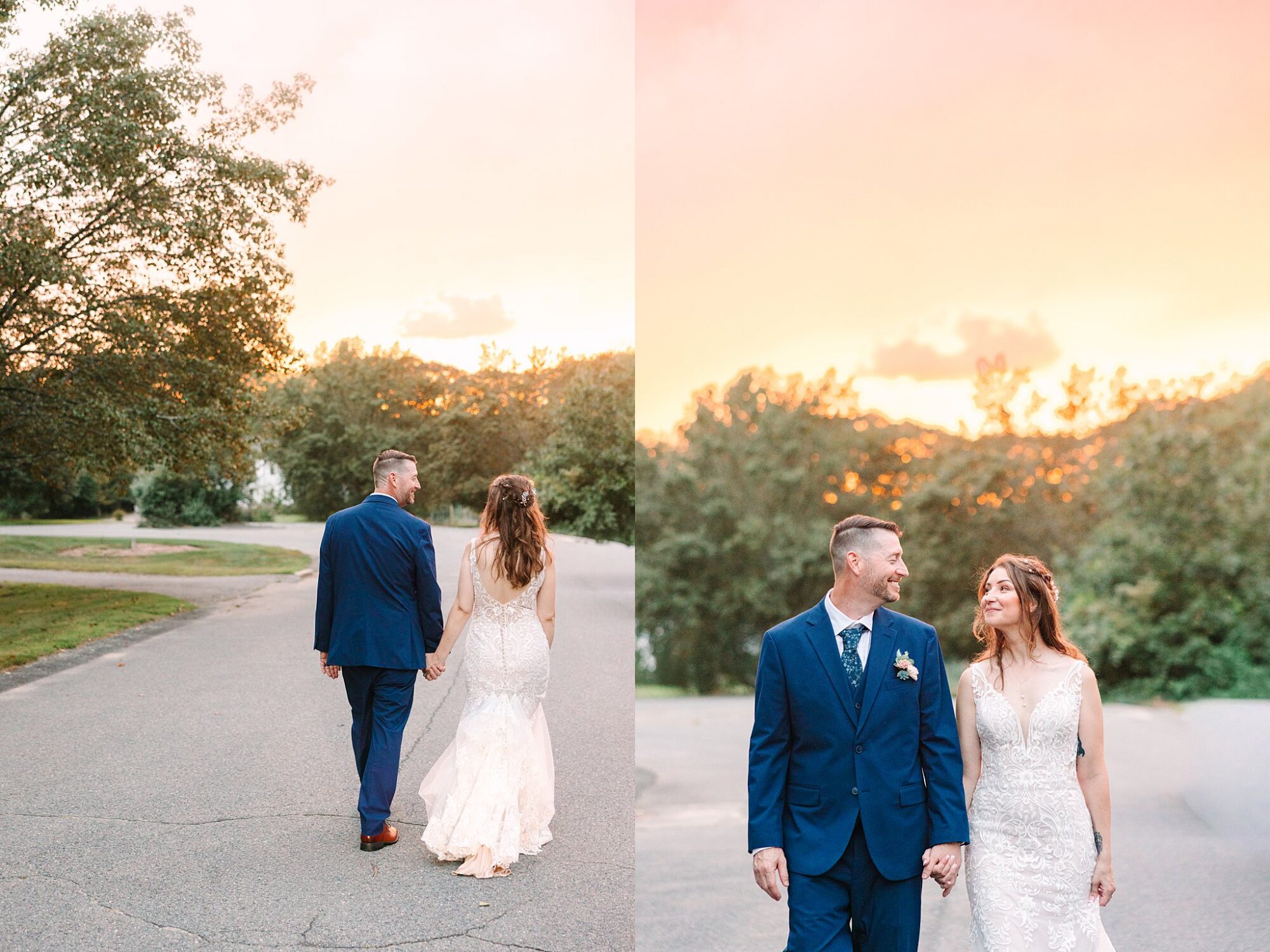 A bride and groom walk hand in hand on a quiet road at sunset, smiling at each other and dressed in wedding attire, with trees and a glowing sky in the background.