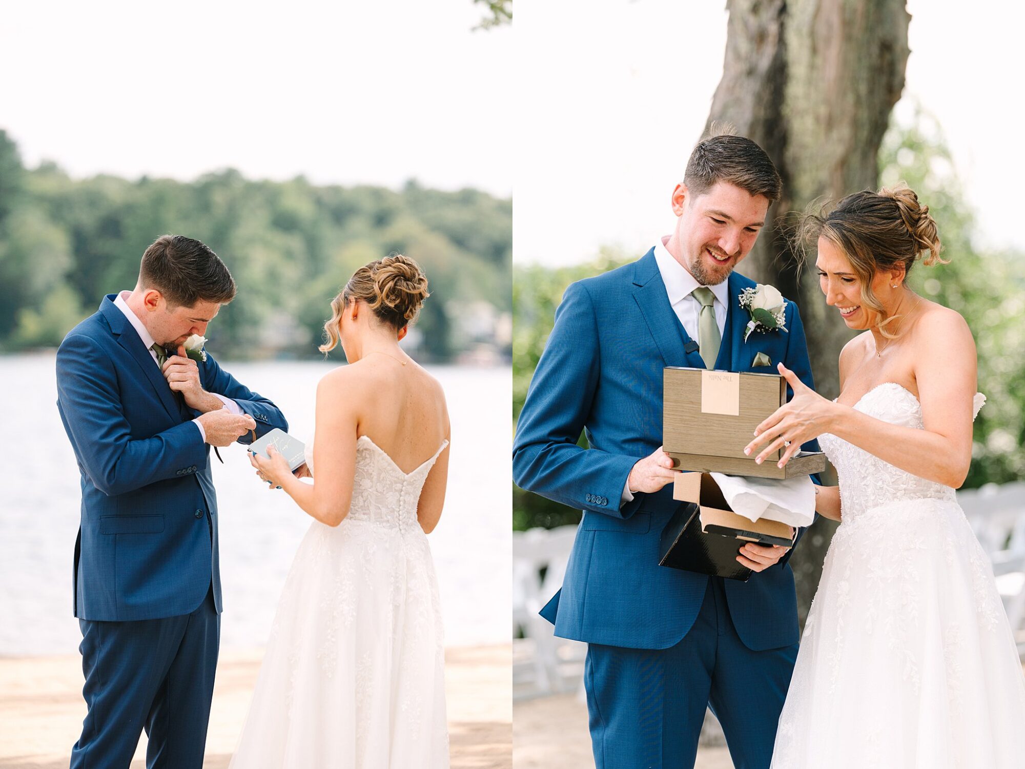 A bride and groom stand outdoors by the water, exchanging gifts and smiling. The groom wears a blue suit, and the bride wears a strapless white dress. Trees and chairs are visible in the background.