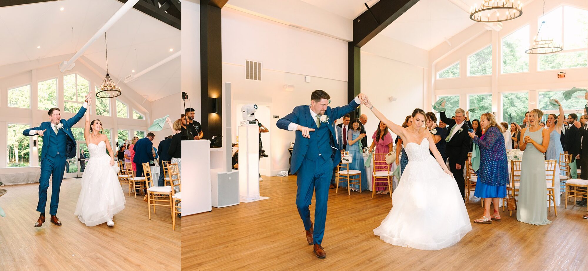 A bride and groom joyfully dance into their wedding reception as guests cheer. The spacious venue has high ceilings, large windows, and wooden floors, creating a bright and festive atmosphere.